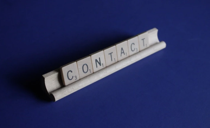Fichas de letras que forman la palabra CONTACT sobre un fondo azul